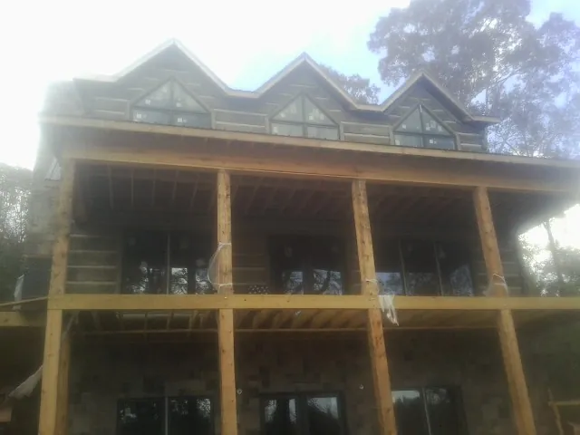 Dormers and porch framing on a large log home under construction — Roof Coating work by our crew in Chichester